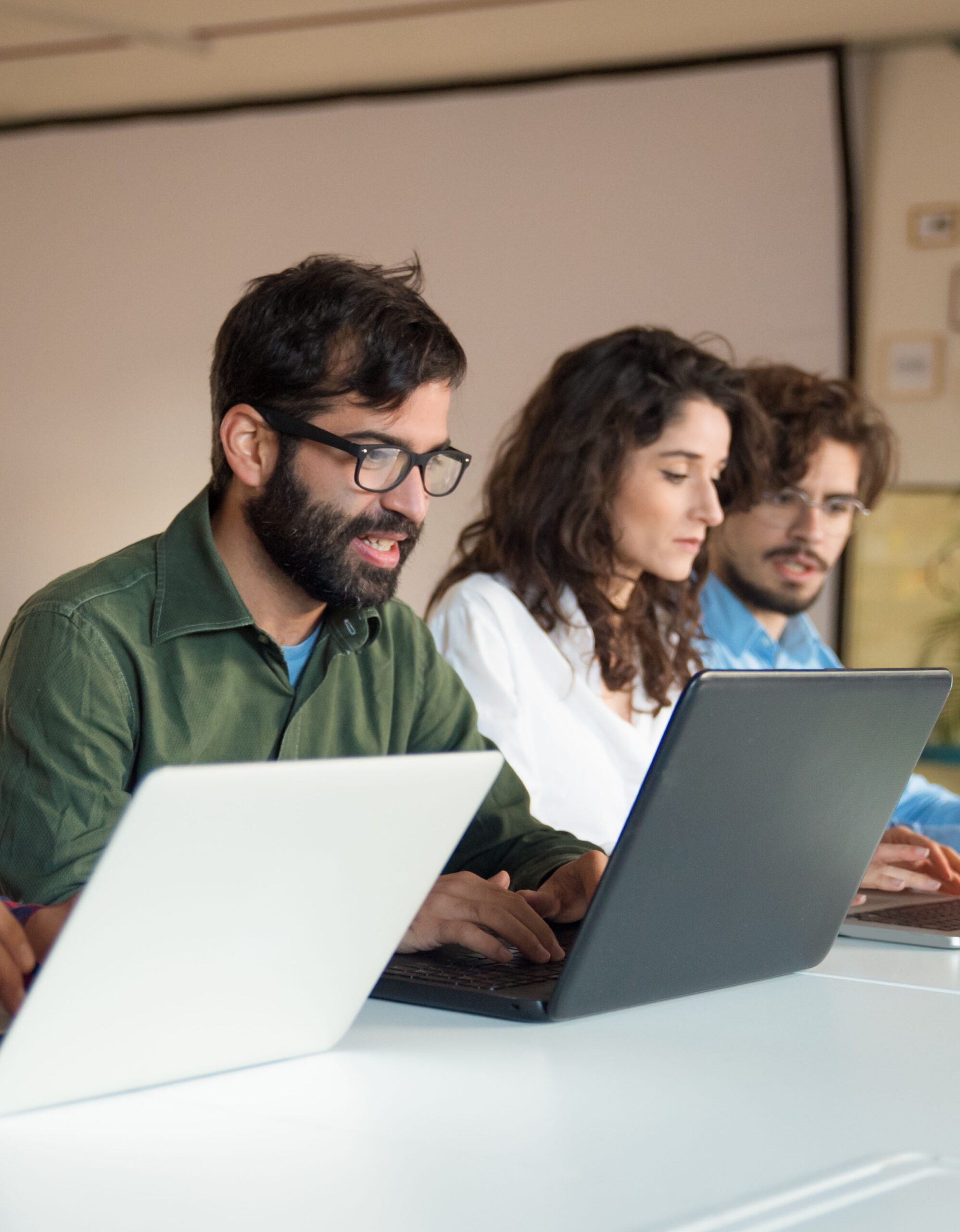 Startup team collaborating on project, using laptops Startup team collaborating on project, using laptops at conference table. Business colleagues in casual working together in contemporary office space. Teamwork concept